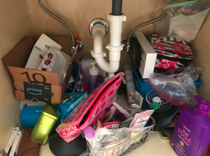 A photo showing a disorganized area under the sink before organizing.