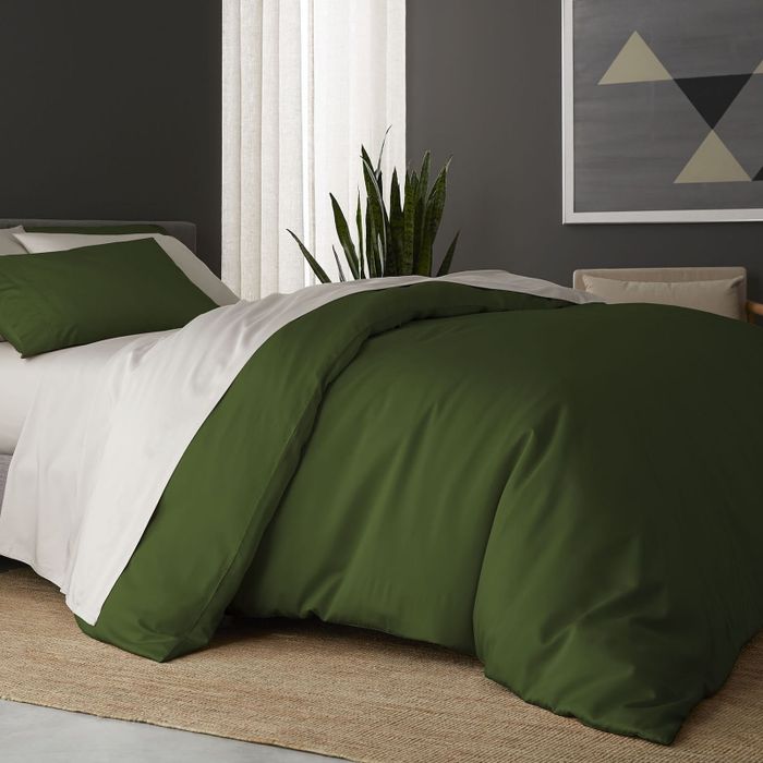 A sheet set in pristine white paired with a forest green duvet.
