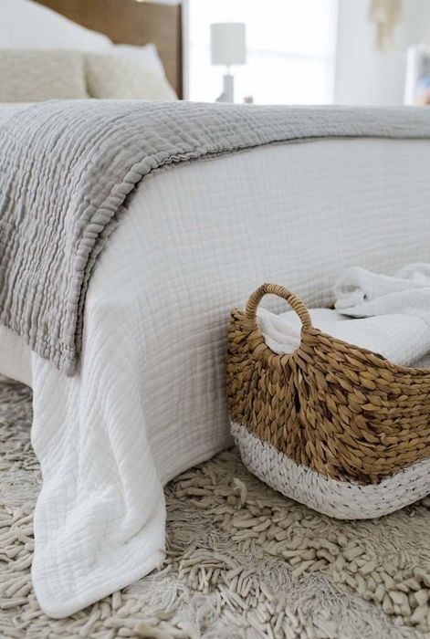 A grey throw and a white throw draped on a bed