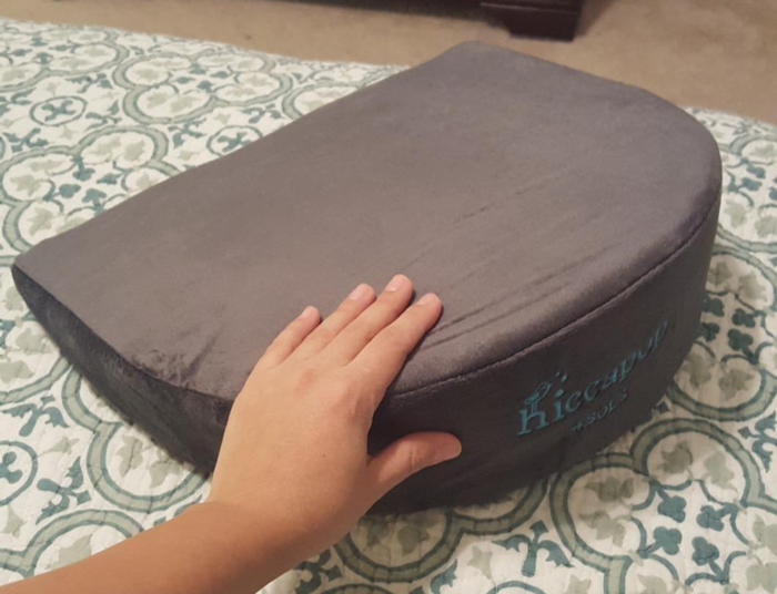 Reviewer gently touching the gray wedge pillow