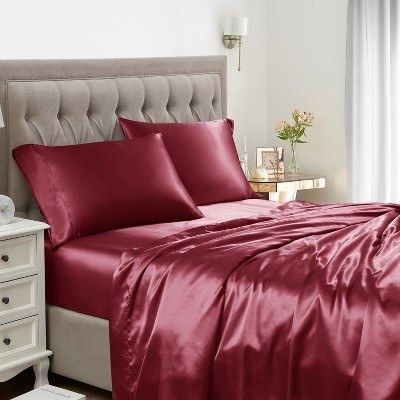 A luxurious red bed set, complete with full bedding, a quilted headboard, and a stylish table lamp.