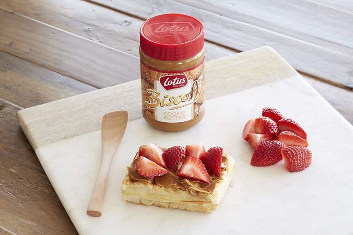 The jar of cookie butter placed next to toast and strawberries.