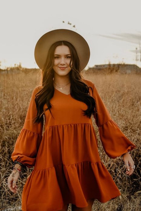 Reviewer wearing the long sleeve dress in a vibrant orange shade.