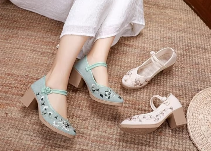 A model is seen wearing green shoes while sitting beside a matching pair in white.