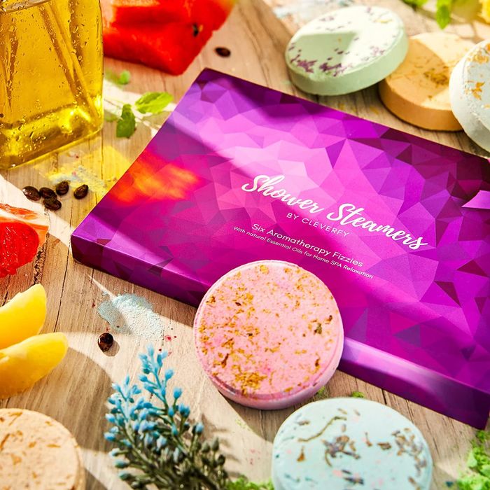 The box containing shower steamers, surrounded by loose, scattered steamers for a relaxed aesthetic.