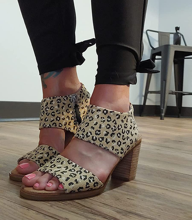 Another reviewer showing off a pair of open-toed, cheetah-print sandals with a block heel.