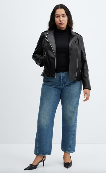 A model is wearing a black leather jacket, a black turtleneck, blue jeans, and black heels.