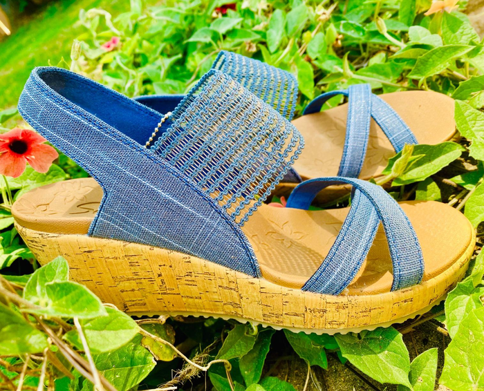 A picture of a reviewer showcasing their blue sandals on grass.