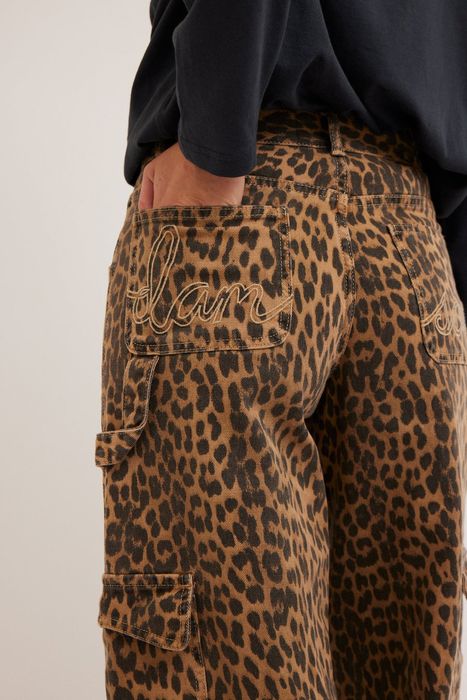 Close-up of a person rocking leopard print jeans with embroidered text on the back pocket