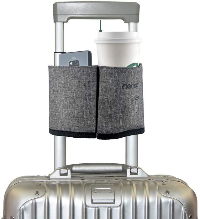 A picture showing a gray cup holder with a Starbucks coffee and a cellphone, both attached to the handle of a carry-on suitcase.