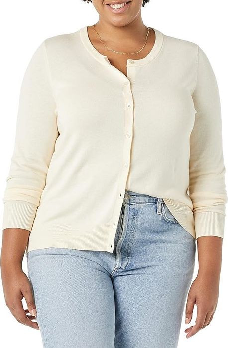 A person dressed in a buttoned-up cardigan and light blue jeans, featured in a shopping article.