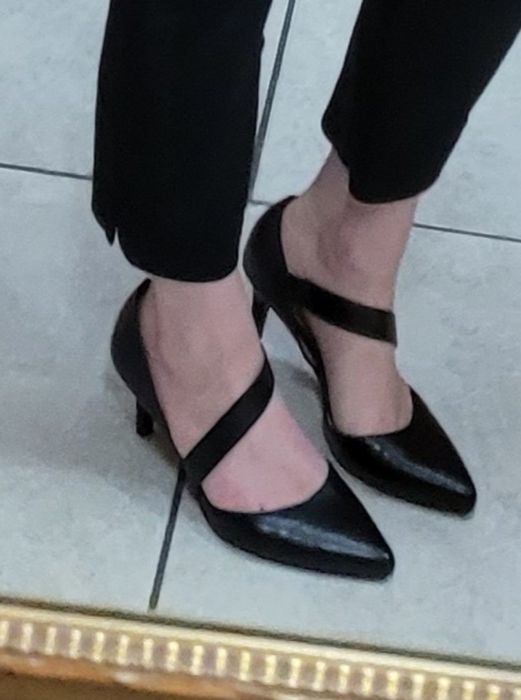 A photo of a reviewer wearing black pants paired with the pointed-toe pumps in black.