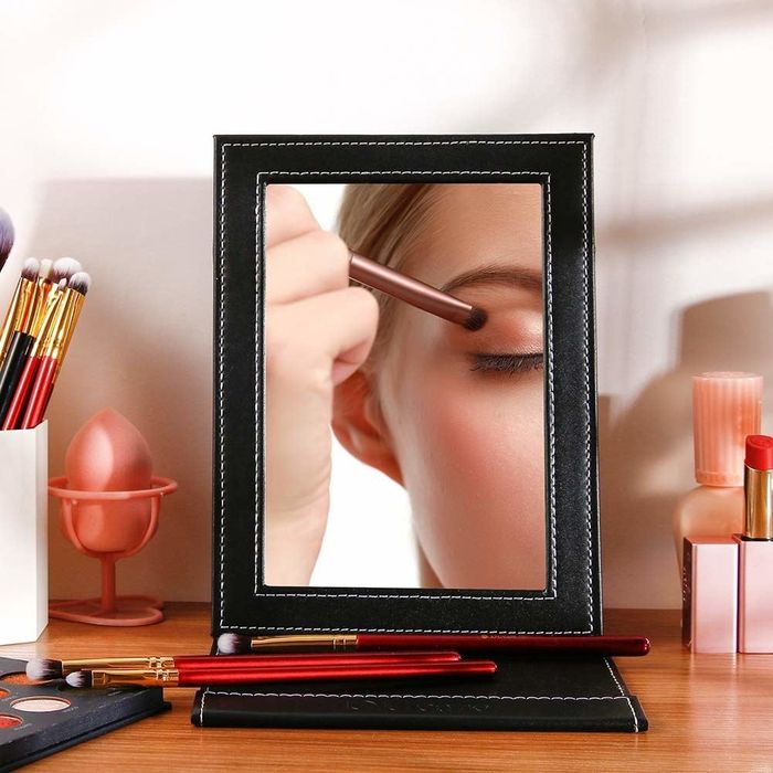 A model's reflection while applying makeup using the desk mirror.