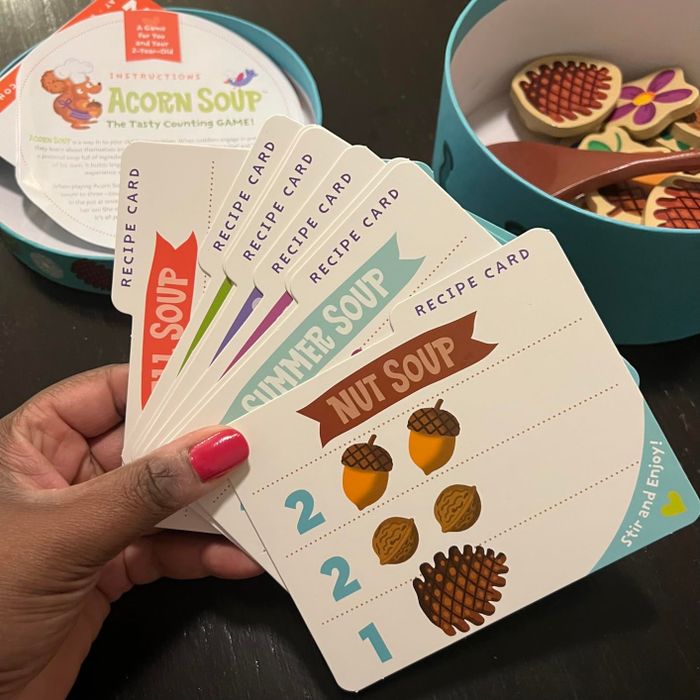A hand is holding a variety of recipe cards for the game.