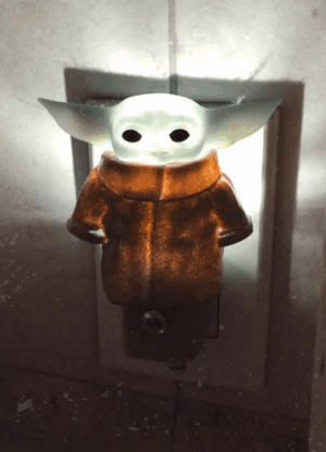 a gif showing the Baby Yoda night light glowing in both light and dark settings