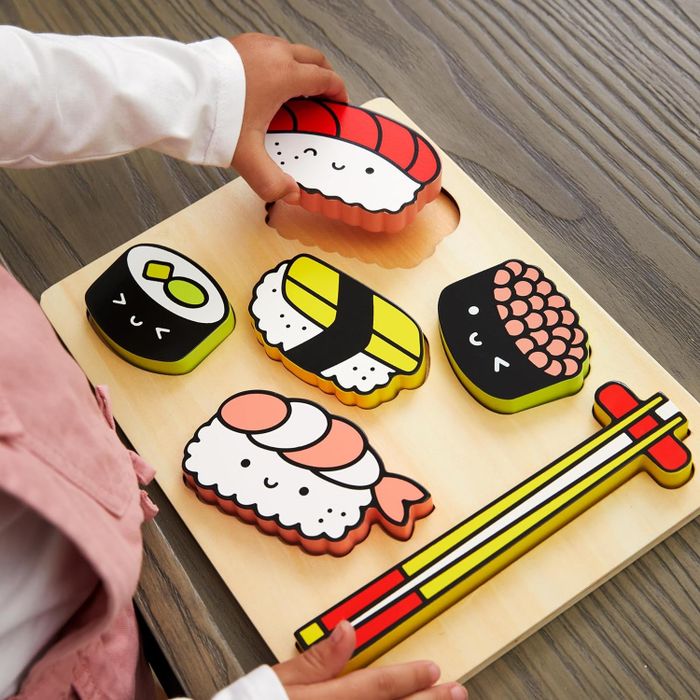 A child is having fun playing with sushi-themed wooden toys on a table.
