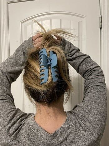 A reviewer showcasing their hair secured with a large blue clip.