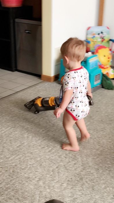 A photo from the reviewer showing their child playing with the toy vacuum.