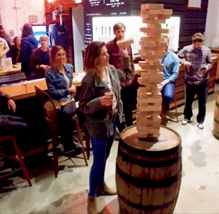 Adults having fun playing a game on top of a barrel