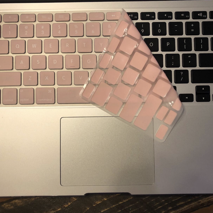 A pink keyboard cover partially covering a laptop keyboard.