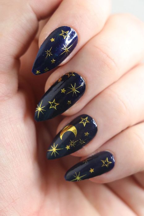 A close-up of nails adorned with celestial-themed decals