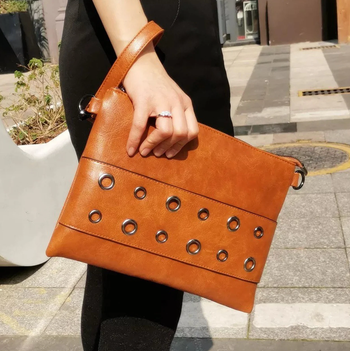 A model holding a brown envelope clutch.