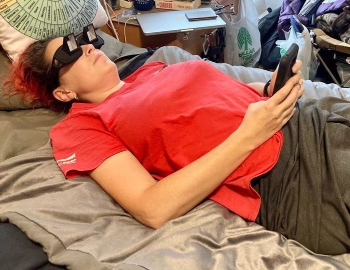 A reviewer comfortably wearing the spectacles while lying down and using their phone.