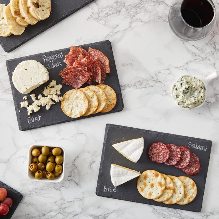 Black mini cheese boards with cheeses and meats labeled in chalk.