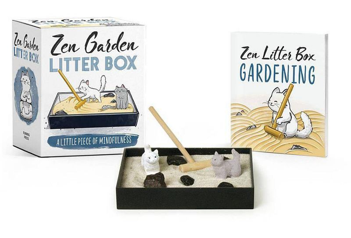 A miniature zen garden complete with a rake, two cats, sand, and small rocks.