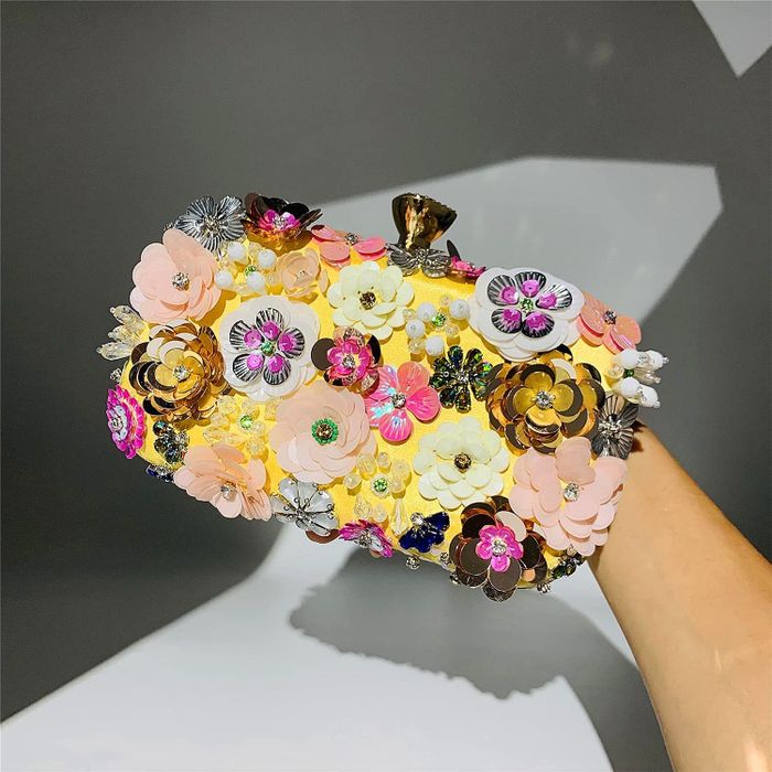 A model holding a yellow floral clutch, showing off its bright and lively design.