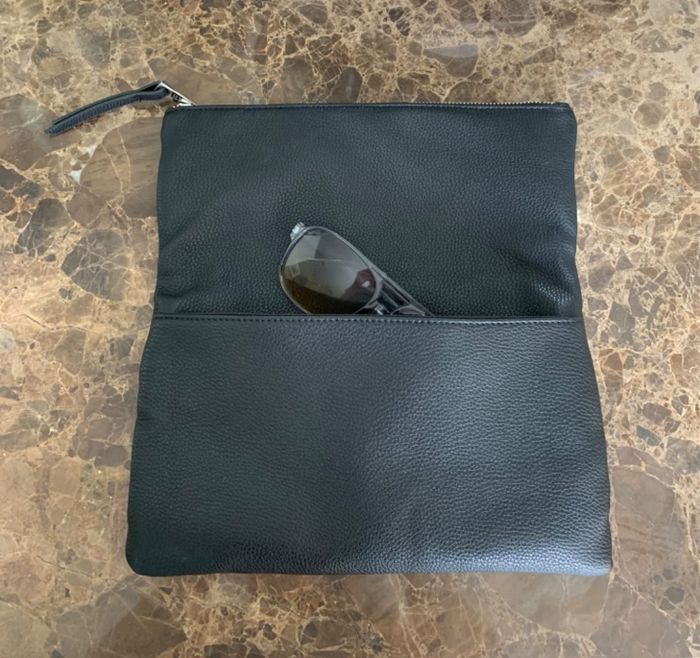 A reviewer's photo of a clutch, with the flap open and sunglasses placed inside.