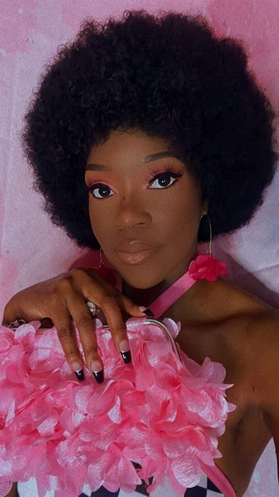 A reviewer is holding up a pink clutch purse, showcasing its style.