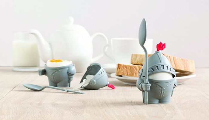 Two egg holders; one set up and standing, the other laying down with the helmet and spoon detached