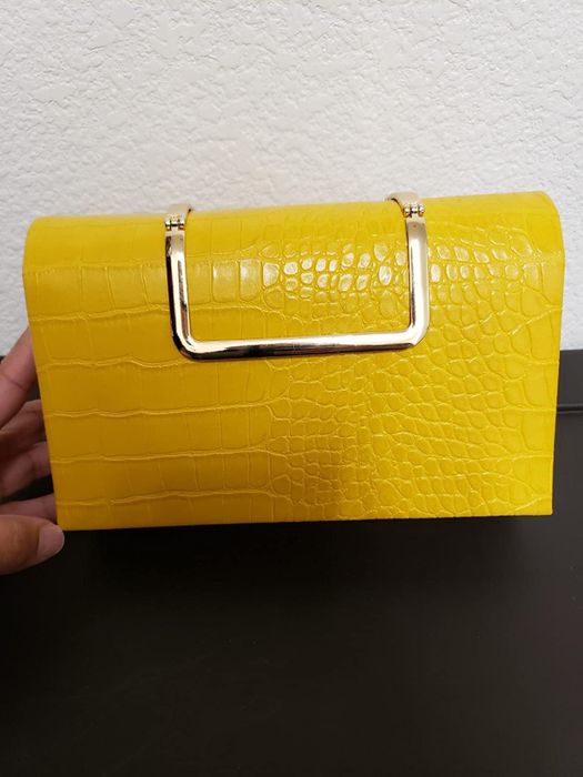 A reviewer displaying a yellow clutch purse