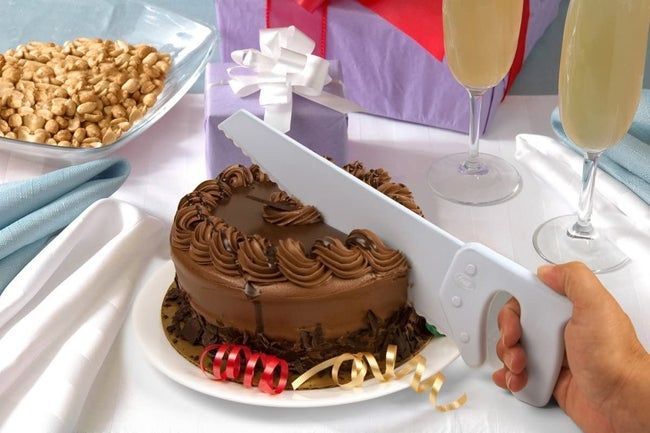 A hand using the knife to slice a chocolate cake