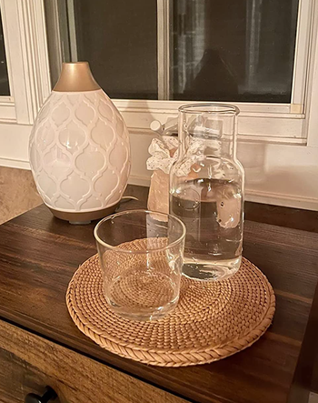 A small glass carafe sitting next to a matching glass cup.