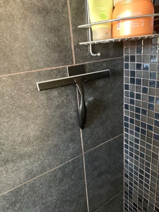 The squeegee conveniently hangs on the adhesive hook that is included with the product.