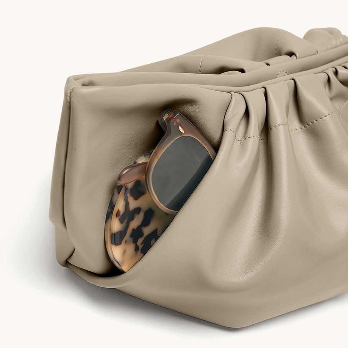 A gray clutch featuring sunglasses neatly placed in the front pocket.