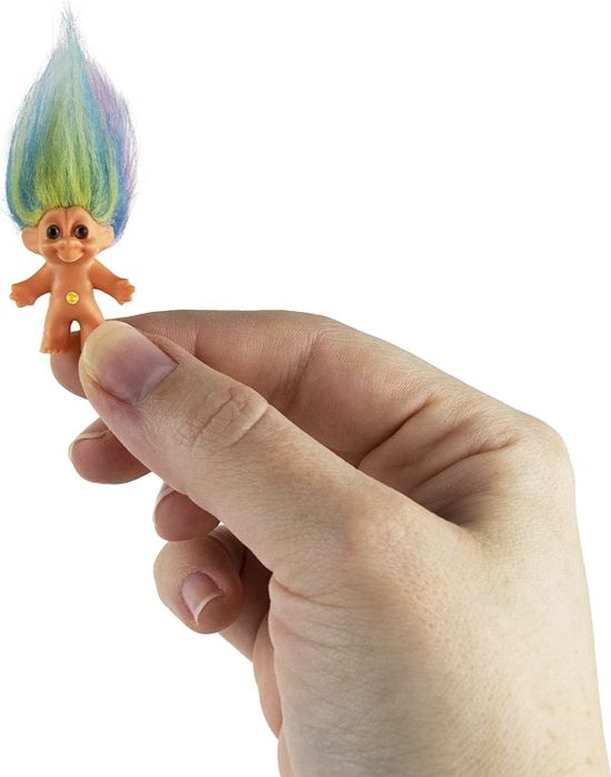 A model holding a small, colorful troll doll with vibrant, multicolored hair.