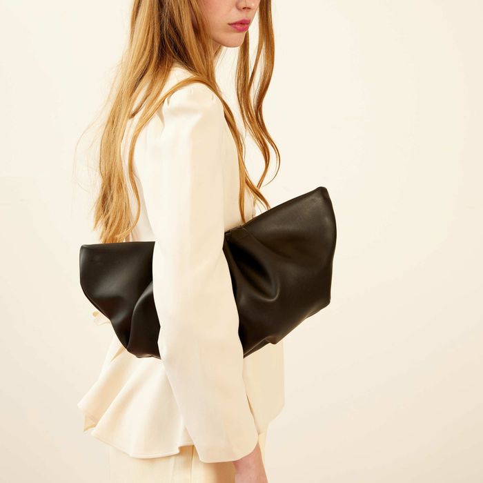 A model confidently carrying a clutch pouch tucked under their arm.