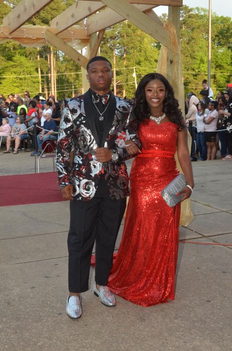 A reviewer holding a silver clutch, posing with their prom date.