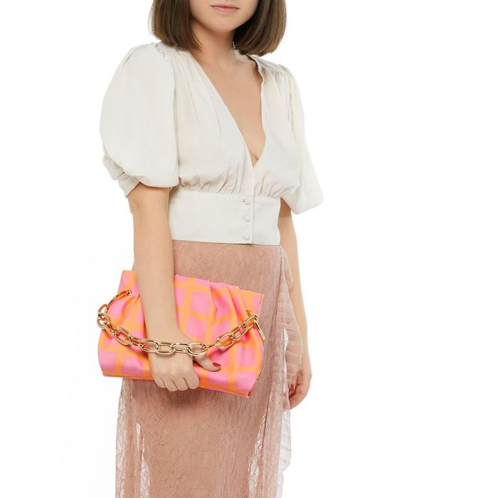 A model posing with a pink and orange tie-dye clutch.