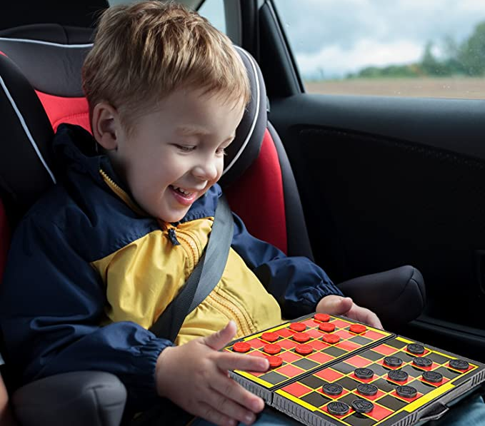 A child playing checkers with a board on their lap while seated in a carseat.