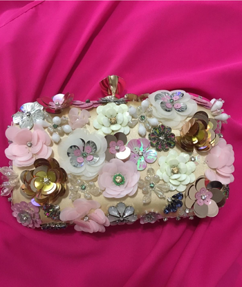 A photo of the floral clutch placed on a pink background, showing its vibrant details.