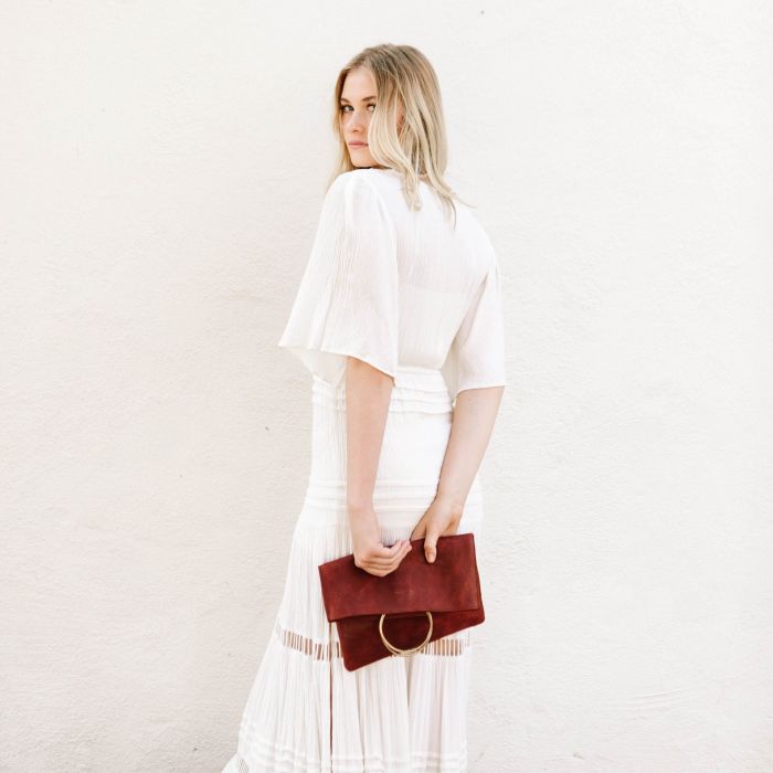 woman holding a vibrant red leather clutch pouch