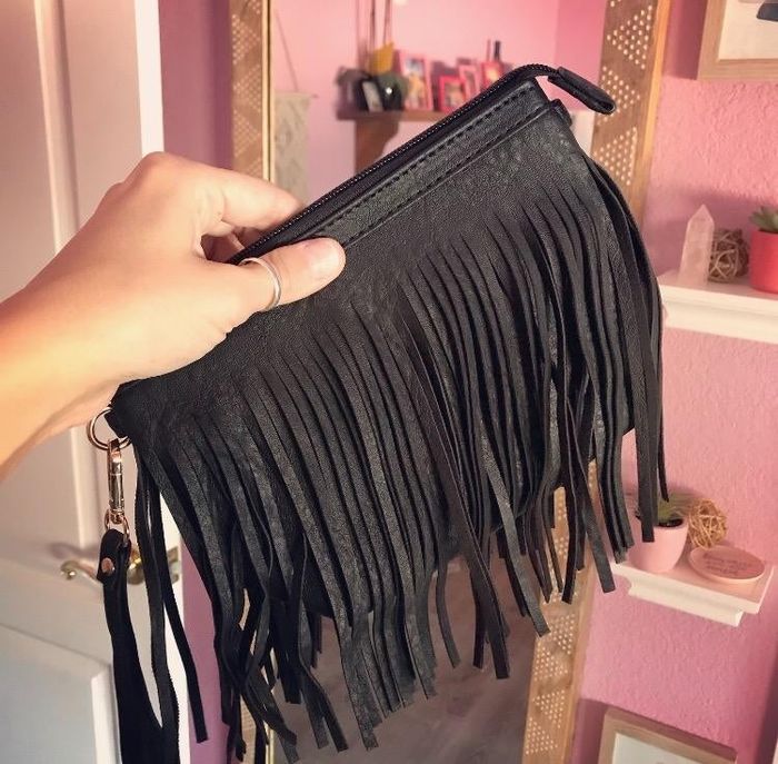 A reviewer holding a black fringed clutch.
