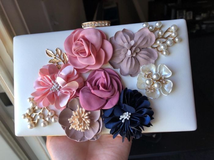 A reviewer showcasing a white floral clutch