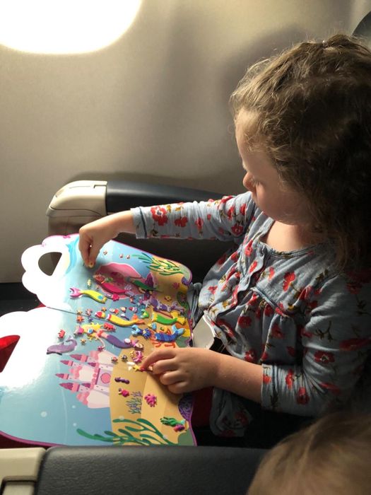 A child enjoying the sticker book during a flight.