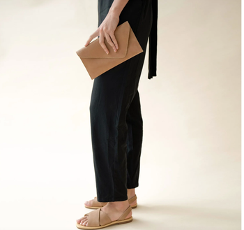 A side view of a model holding a beige clutch.