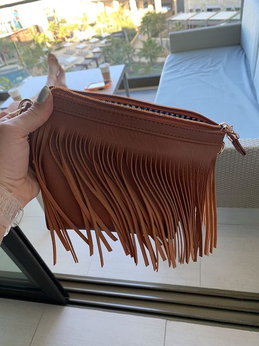 A reviewer holding a brown fringed clutch.